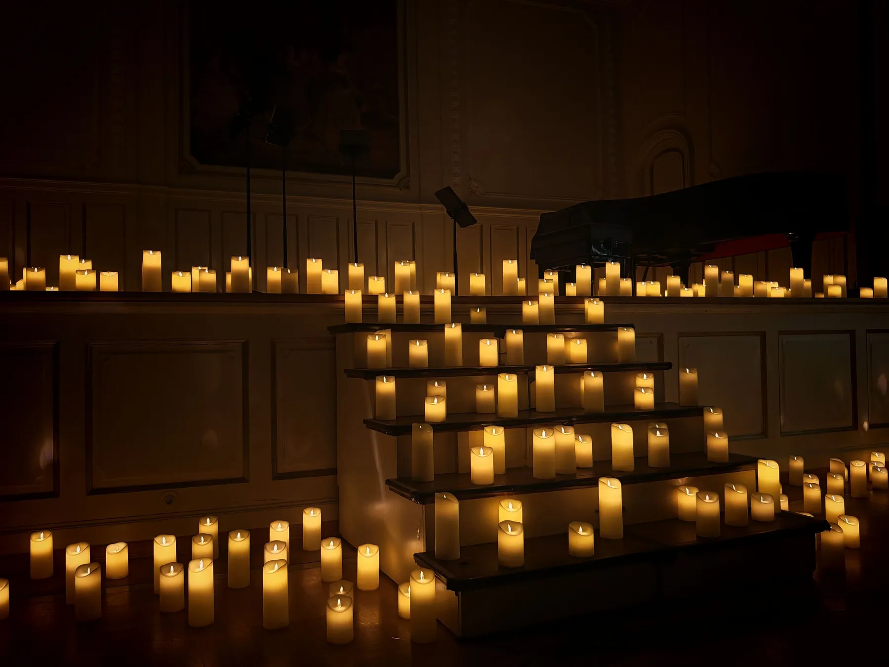 Rows of candles climbing a set of steps inside a darkened hall