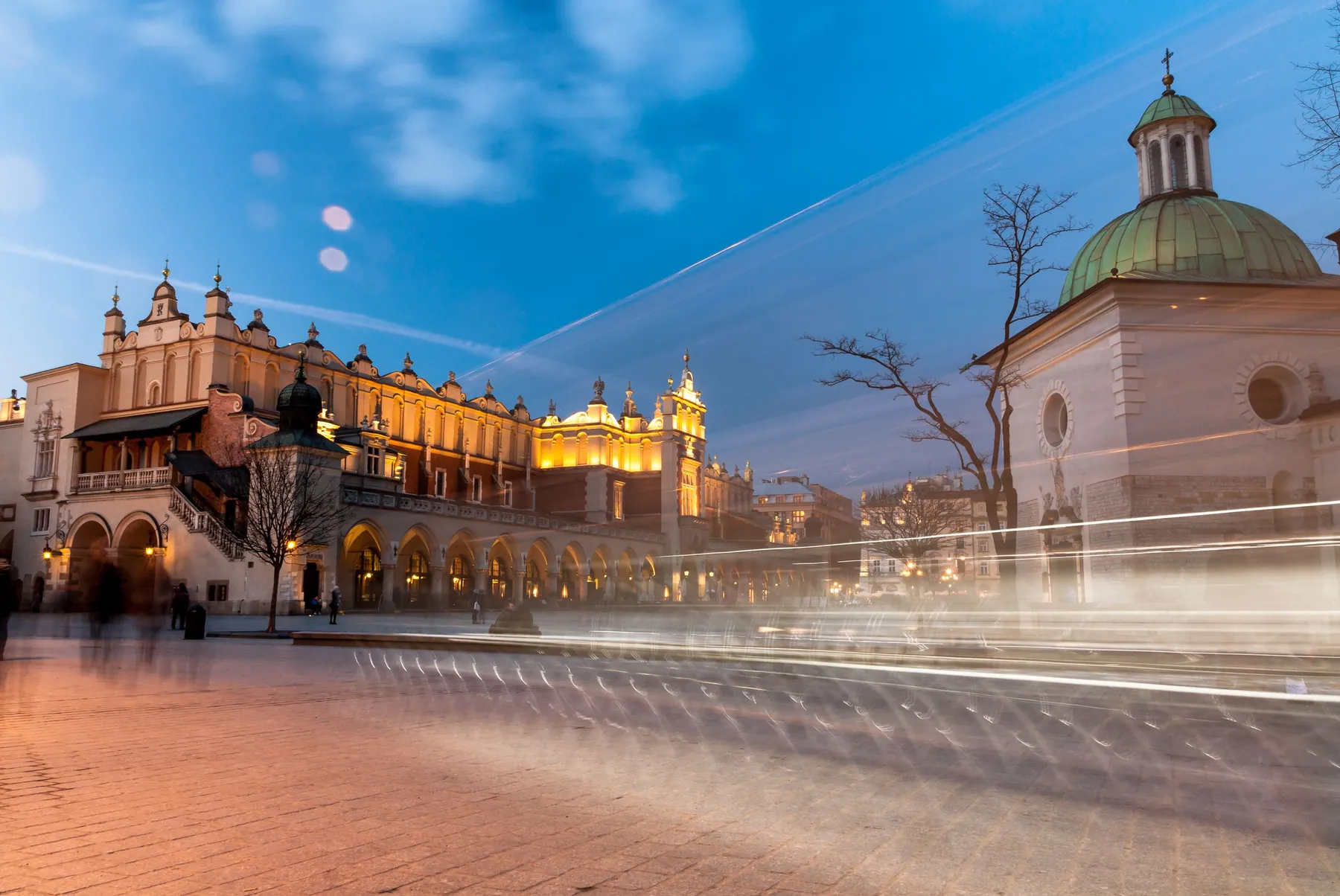 The Cloth Hall in Kraków's Main Market Square at twilight, with St Adalbert's Church beside it